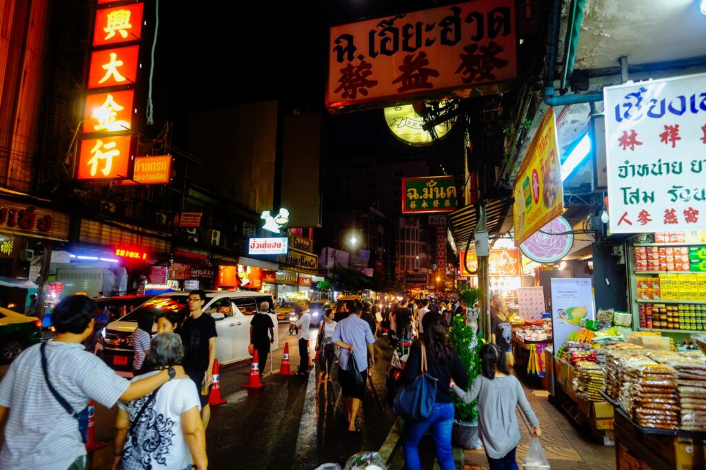 Auf der belebten Yaowarat Road im Viertel Chinatown in Bangkok herrscht nachts reges Treiben. Unzählige Menschen schlendern entlang der Straße und werden von den bunten Lichtern der vielen Geschäfte und Restaurants beleuchtet. Die Vielfalt an Gerüchen und Geräuschen, die sich vermischen, schaffen eine einzigartige Atmosphäre, die das pulsierende Leben und die kulturelle Geschichte von Chinatown widerspiegelt. Das Foto bietet einen faszinierenden Einblick in die lebhafte Stadt und zeigt, wie reich und vielfältig Bangkok und insbesondere Chinatown sind.